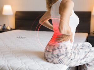 vrouw in bed met rugpijn na slapen