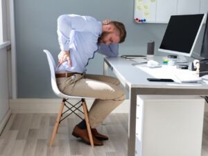 man in kantoor aan bureau met spierpijn rug