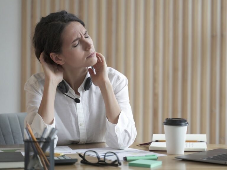 vrouw aan bureau met Spierreuma en stress